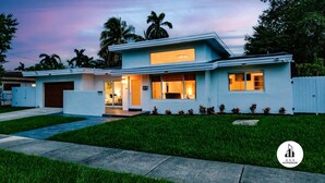 A modern two-story house with a garage, a covered patio, and a well-maintained lawn. - Stylish Aventura Home With Pool on Intercostal (Ojus)