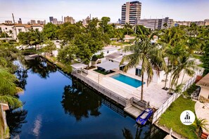 A residential area with a swimming pool, palm trees, and a canal. - Stylish Aventura Home With Pool on Intercostal (Ojus)