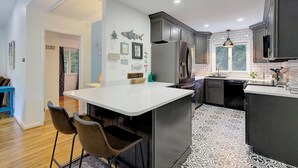 A modern kitchen with a central island, dark cabinetry, and patterned flooring. - "High Tide Tranquility"- Beach w/ BBQ (Port Republic)