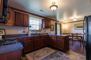 A kitchen with wooden cabinets, a granite countertop, a stove, and a refrigerator.
