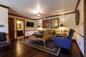 A living room with a sofa, armchairs, a coffee table, and a television.