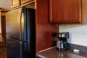 A kitchen with a black refrigerator and a coffee maker on the counter.
