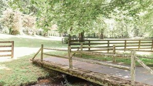 A rustic wooden bridge over a small stream in a park. - The Stables Cottage (Knoxville)