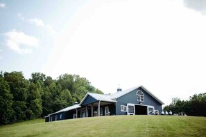 A large, dark-colored building with a prominent arched window and a covered porch area.