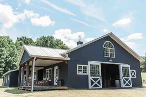 A large, dark-colored barn with a covered porch and a garage.