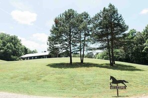 A grassy area with a building in the background and a horse silhouette on a sign.