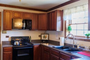 Cocina con gabinetes de madera, microondas, estufa y pileta.