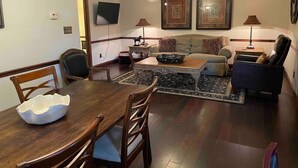 A dining area with a wooden table and chairs, a sofa, and a coffee table. - The Stables Cottage (Knoxville)