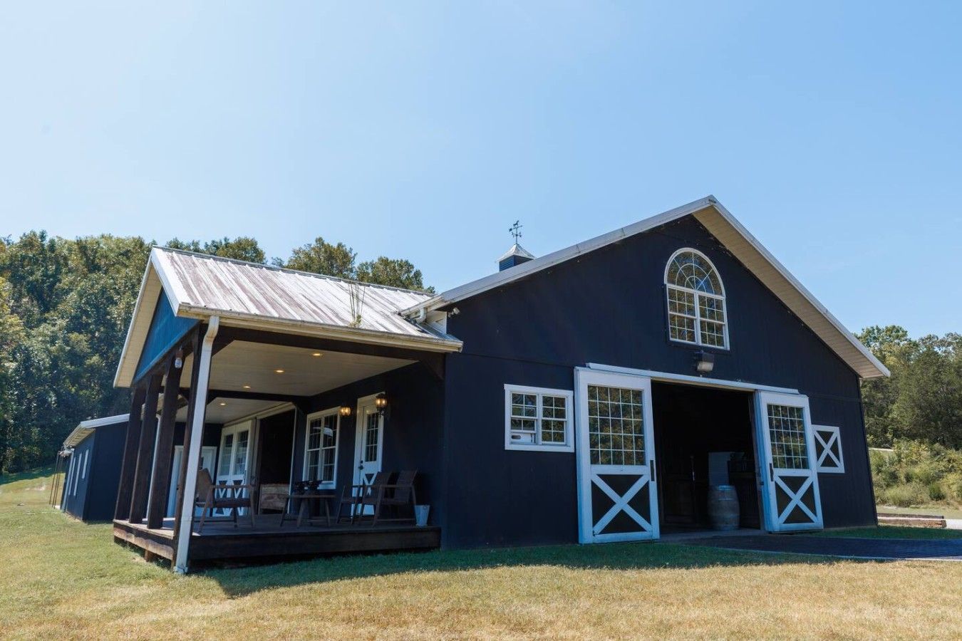 A large barn with a covered porch and open garage doors.
