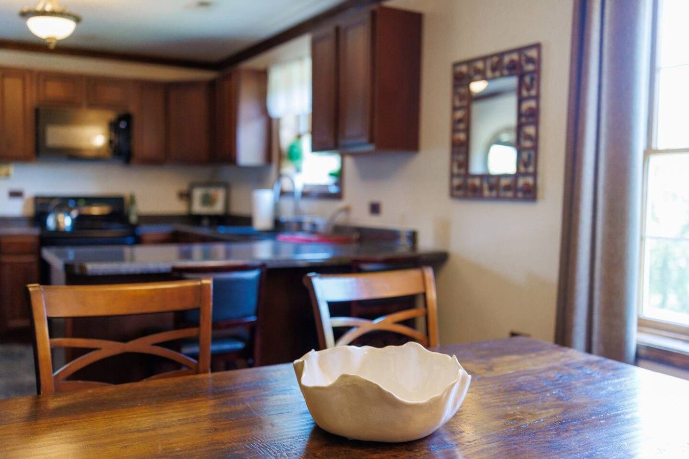 A kitchen with wooden cabinets, a microwave, and a dining area with a wooden table and chairs.