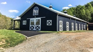 A black barn with white cross windows, a large door, and a covered entryway. - The Stables Cottage (Knoxville)