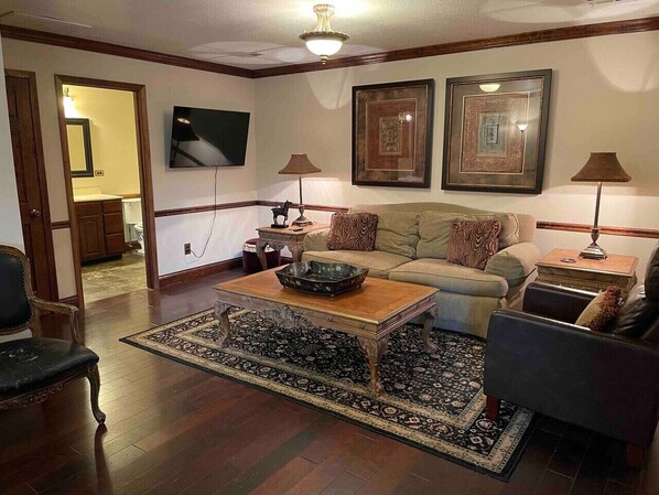 A living room with a sofa, armchairs, a coffee table, and a TV.