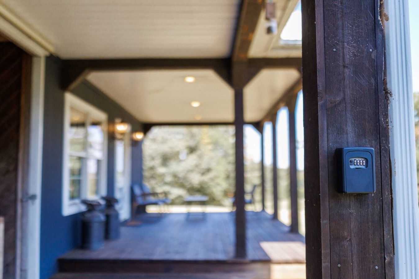 Une véranda couverte avec une balustrade en bois, une porte avec une serrure et une vue sur l’extérieur.