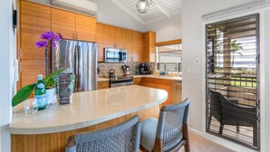 A modern kitchen with wooden cabinets, stainless steel appliances, and a central island with seating.