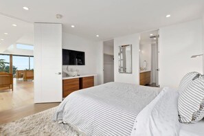 A modern bedroom with a large bed, a white wardrobe, a built-in TV, and a view to the outside. - Ocean View Moss Beach Retreat (Moss Beach)