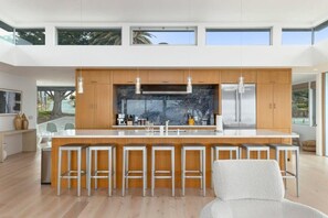 A modern kitchen with a large island, wooden cabinets, and stainless steel appliances.