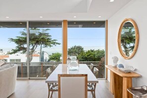 Un comedor moderno con una mesa grande, sillas y vistas al exterior a través de puertas de vidrio.