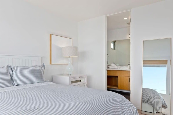 A hotel room with a bed, bedside table, lamp, and a mirror.