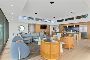 Amplia sala de estar con un conjunto de sofás, una mesa de comedor y una zona de cocina con barra.
