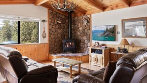 A cozy living room with a stone fireplace, leather sofas, a wooden ceiling, and a television. - Cozy 3BDR - 1 Minute to the Beach! (Tahoe Vista)