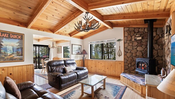 A cozy living room with a stone fireplace, leather sofa, and wooden ceiling beams. - Cozy 3BDR - 1 Minute to the Beach! (Tahoe Vista)