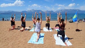 A group of people performing a yoga exercise on a beach with a mountain backdrop. - Cozy 3BDR - 1 Minute to the Beach! (Tahoe Vista)