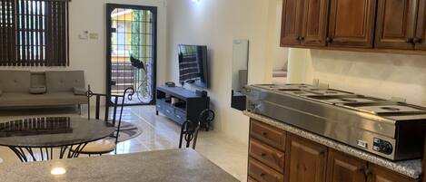 Una cocina con armarios de madera, encimera de granito, estufa y un rincón comedor con sofá y sillas.
