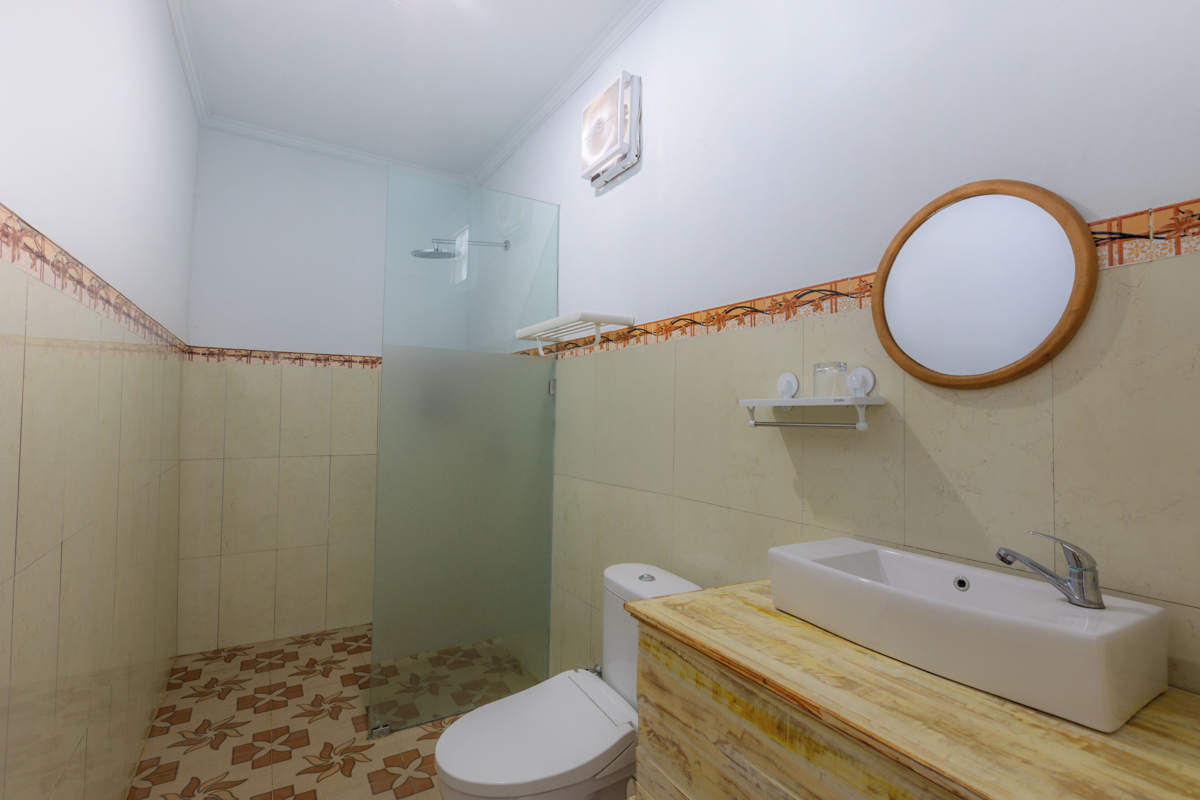 A bathroom with a shower, toilet, sink, and mirror.