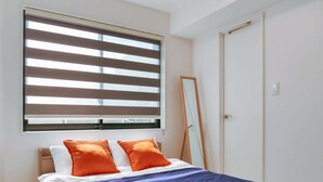 Una camera da letto con un letto, una finestra con persiane, uno specchio e una porta.