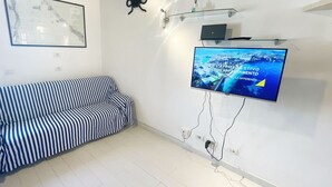 A modern living room with a striped sofa, a mounted TV displaying a cityscape, and a map on the wall.