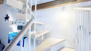 A modern interior with a staircase, a flat-screen TV, and a white door.