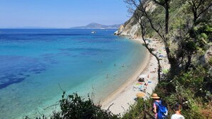 Una playa costera con aguas turquesas cristalinas, una orilla arenosa y acantilados rocosos.