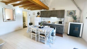 A compact kitchen with a dining area, wooden beams, a microwave, and a small refrigerator.