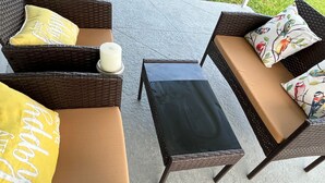 A wicker sofa set with cushions, a small table, and a candle. - Gorgeous 3Bed in the heart of South Florida (Fort Lauderdale)