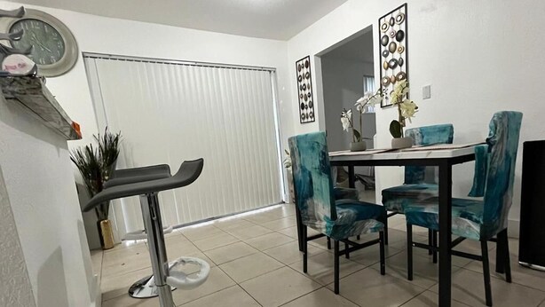 A dining area with a table and chairs, a bar stool, and a clock on the wall. - Gorgeous 3Bed in the heart of South Florida (Fort Lauderdale)