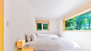 Une chambre à coucher avec un lit, une table de chevet, une fenêtre donnant sur un paysage verdoyant et une petite fenêtre située au-dessus du lit.