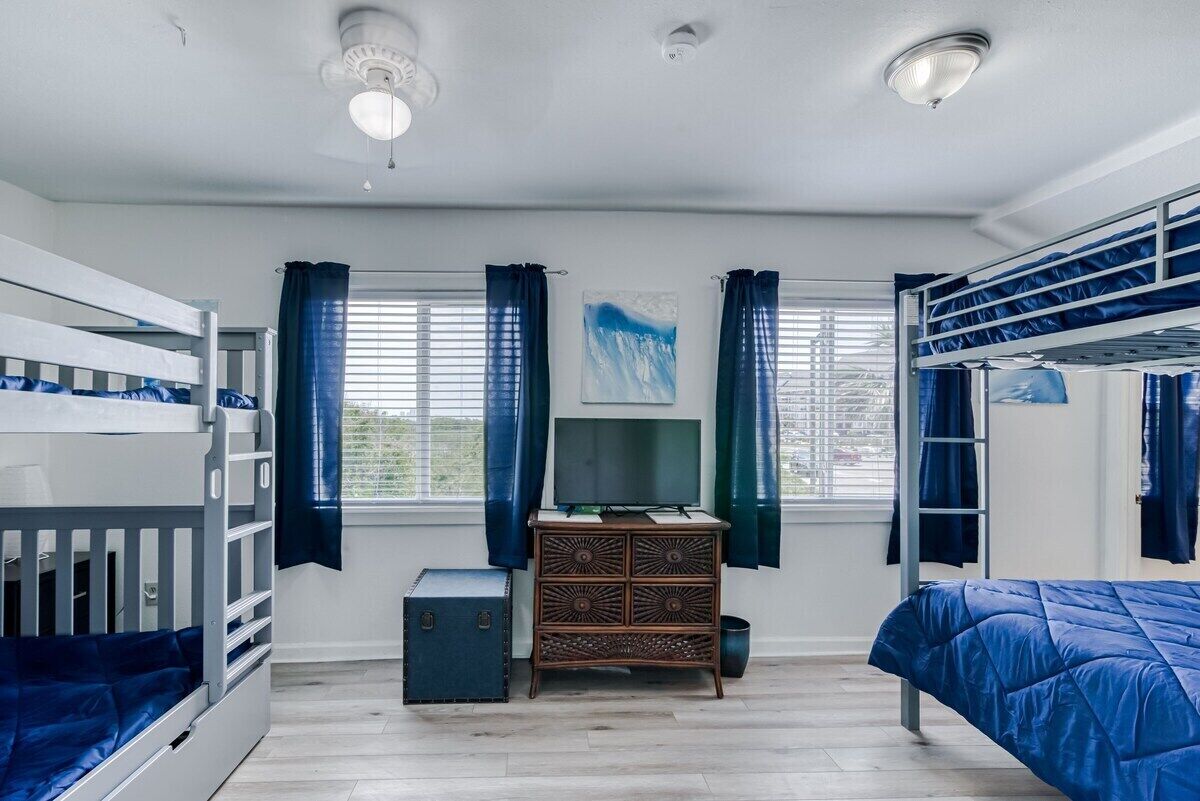 Een studentenkamer met stapelbedden, een dressoir en een televisie.