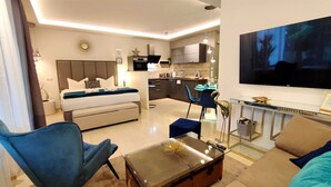 A modern hotel room with a bed, a sofa, a dining area, and a kitchen. - Homely Stay -  Studio P1 (München)