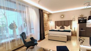 A modern hotel room with a bed, seating area, and a dining table. - Homely Stay -  Studio P1 (München)