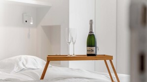 A bed with white linens, a wooden bedside table with a bottle of champagne and two glasses on it. - Seaflow-holiday apartment with frontal sea view (Oostduinkerke)