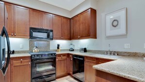 Cocina con armarios de madera, microondas, estufa y lavavajillas.