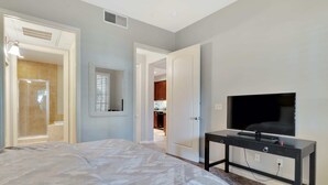 Un dormitorio con cama, televisor y baño con ducha e inodoro.