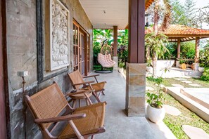 Relax in a serene outdoor seating area surrounded by lush greenery and a well-maintained garden.