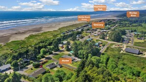 Vue aérienne d’une zone résidentielle côtière, avec des éléments identifiés, notamment une plage, un parc, une rivière, une épicerie et une maison.