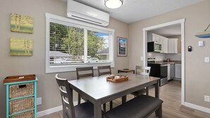 Une cuisine moderne avec des meubles blancs, un four à micro-ondes encastré et un coin repas comprenant une table et des chaises.
