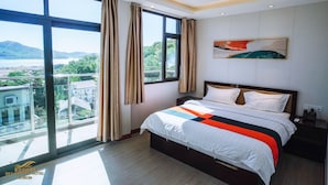 A modern hotel room with a large bed, a view of the city, and a balcony. - Sky Garden Hotel (Coron)