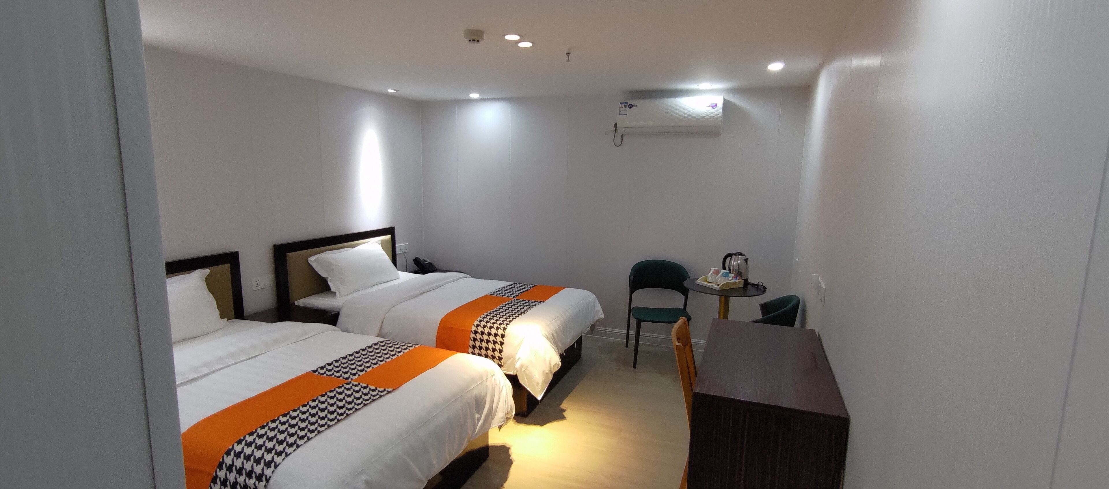Een hotelkamer met twee bedden, een bureau, een stoel en een airconditioning.