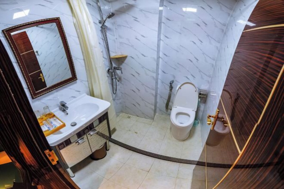 A bathroom with a sink, mirror, toilet, and shower.