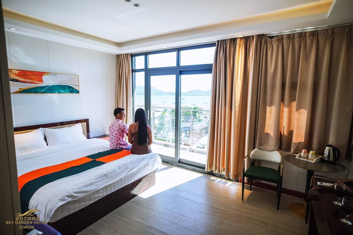 Quarto de hotel com cama grande, vista da cidade e varanda.