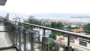 A balcony with a metal railing overlooking a coastal area with buildings and boats. - Sky Garden Hotel (Coron)